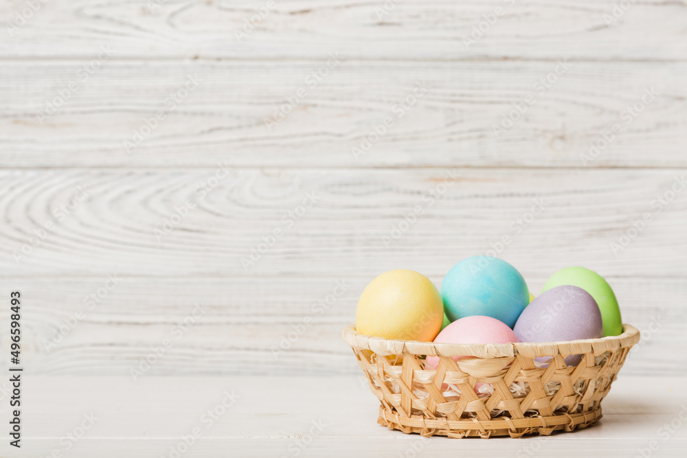 Multi colors Easter eggs in the woven basket on colored background . Pastel color Easter eggs. holiday concept with copy space Multi colors Easter eggs in the woven basket on colored background . Pastel color Easter eggs. holiday concept with copy space