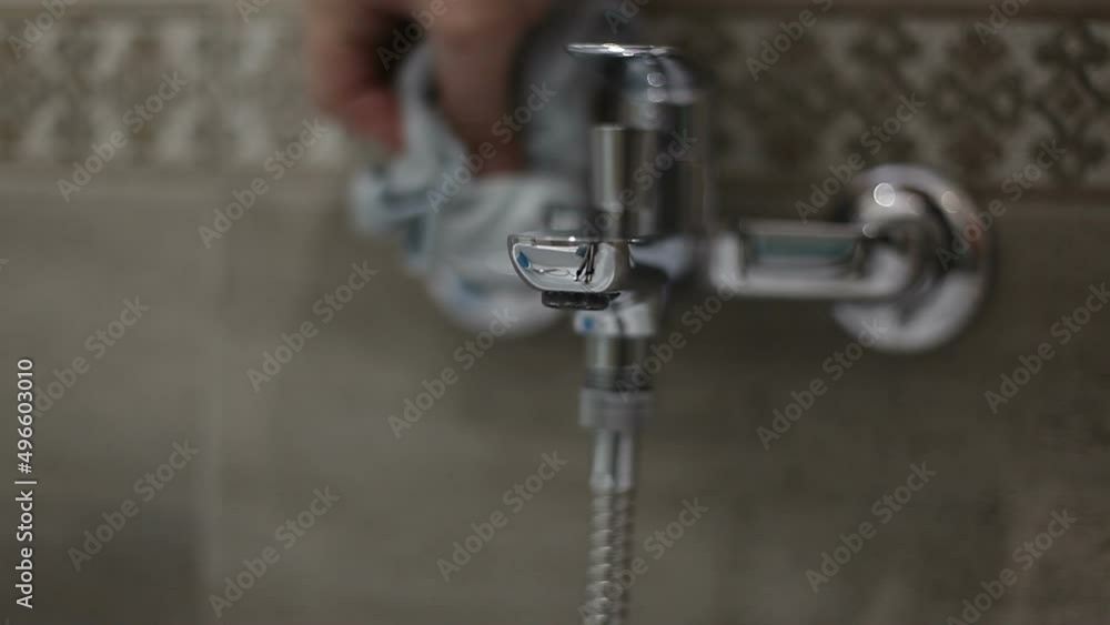 A man cleans the faucet in the bathroom. The housekeeper polishes the faucet to a shine. A man cleans the faucet in the bathroom. The housekeeper polishes the faucet to a shine.