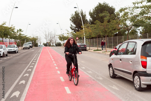 Front view of a young girl riding her bicycle in the bike lane in traffic.