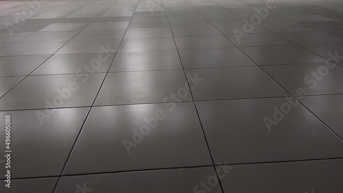 White ceramic tile floor in dim light room with soft light and shadow from outside of the building