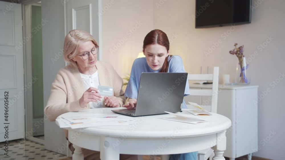 Adult granddaughter helps grandmother pay for purchases on the Internet using a credit card Adult granddaughter helps grandmother pay for purchases on the Internet using a credit card