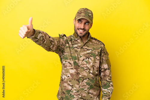 Military man isolated on yellow background giving a thumbs up gesture