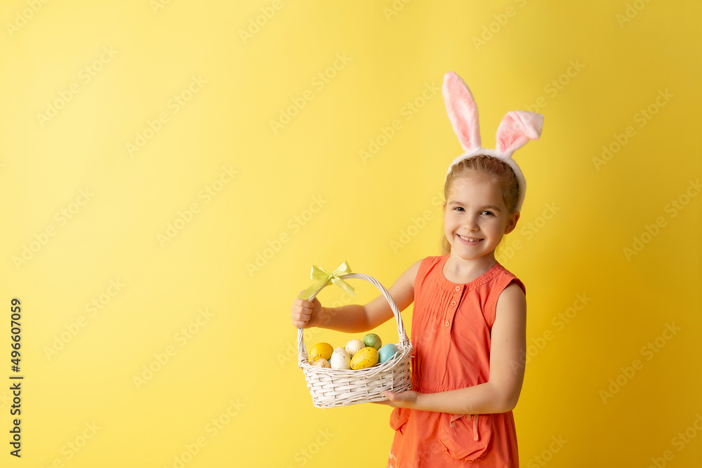 Beautiful cute little girl in Easter bunny ears smiling and holds spring bouquet of tulips on a yellow background Beautiful cute little girl in Easter bunny ears smiling and holds spring bouquet of tulips on a yellow background