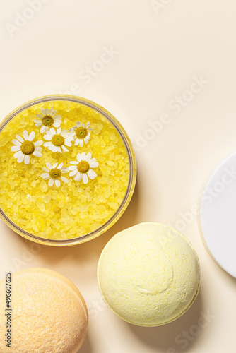Bath salt sea and bath bomb with herbal extract of chamomile, sea salt crystals in jar, neutral beige spa background. Close up body care cosmetics, natural organic product, herbal medicine