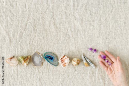 Row of healing crystals, female hands holding small amethyst gemstones rocks for magic crystal ritual, chakra relaxation, reiki healing therapy, aura readings. Top view magic minerals