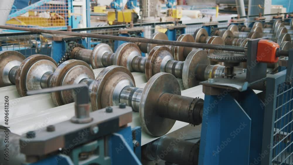 Close up metal sheet forming machine in metalwork factory. Steel rollers in metalforming machine for production roof tile in factory Close up metal sheet forming machine in metalwork factory. Steel rollers in metalforming machine for production roof tile in factory