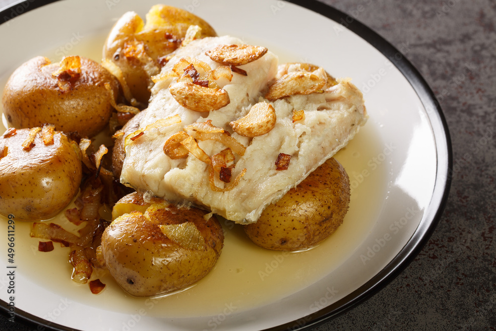 Portuguese Bacalhau a Lagareiro salted cod baked in oil with potatoes close-up in a plate on the table. horizontal Portuguese Bacalhau a Lagareiro salted cod baked in oil with potatoes close-up in a plate on the table. horizontal