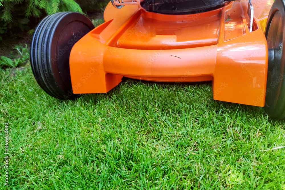 Modern lawn mower on green grass. Spring garden works concept. Outdoor gardening in sunny day backgroud Modern lawn mower on green grass. Spring garden works concept. Outdoor gardening in sunny day backgroud