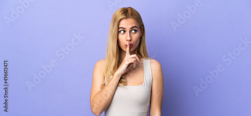 Young Uruguayan blonde woman over isolated background showing a sign of silence gesture putting finger in mouth photo