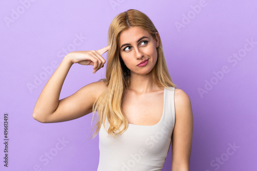 Young Uruguayan blonde woman over isolated background making the gesture of madness putting finger on the head