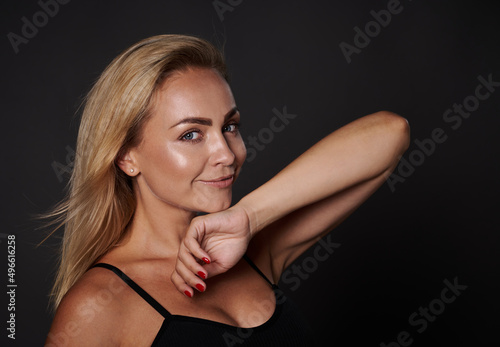 Headshot attractive beautiful woman with shining glowing fresh tanned skin, in underwear cutely smiling looking at camera isolated over black background with copy ad space. Body positivity concept