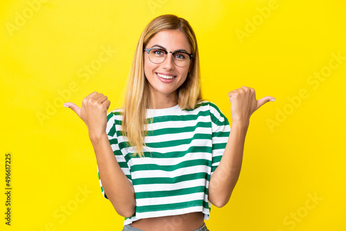 Blonde Uruguayan girl isolated on yellow background with thumbs up gesture and smiling © luismolinero