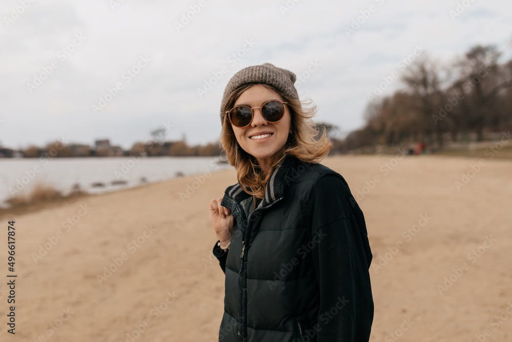 Close up outside portrait of european stylish woman in sunglasses and cap is smiling at camera while traveling Close up outside portrait of european stylish woman in sunglasses and cap is smiling at camera while traveling