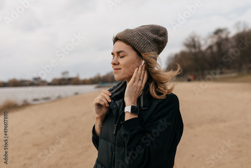 Profile picture of charming girl is listening music with closed eyes and happy smile while walking on the spring beach