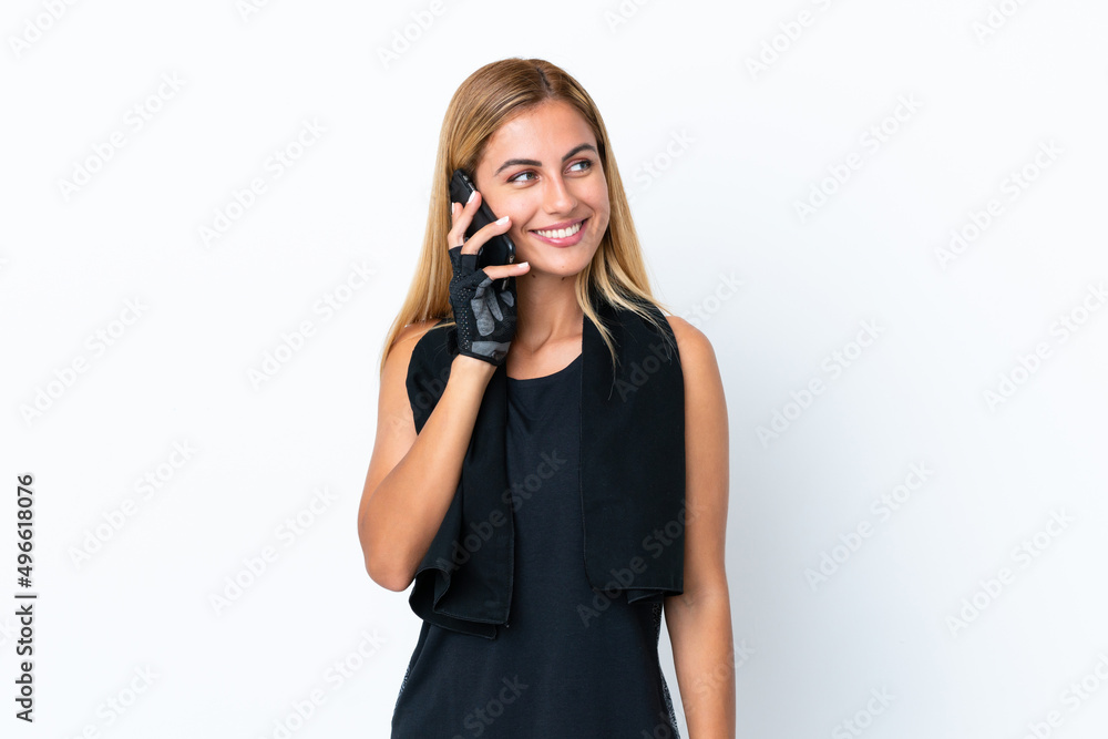 Blonde Uruguayan sport girl isolated on white background keeping a conversation with the mobile phone with someone Blonde Uruguayan sport girl isolated on white background keeping a conversation with the mobile phone with someone