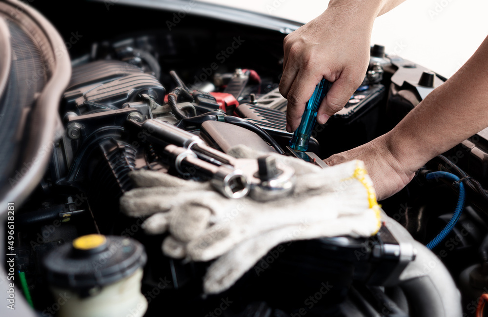Car service man use screwdriver to remove part of the car in the engine room and wrench and glove on engine car service concept Car service man use screwdriver to remove part of the car in the engine room and wrench and glove on engine car service concept