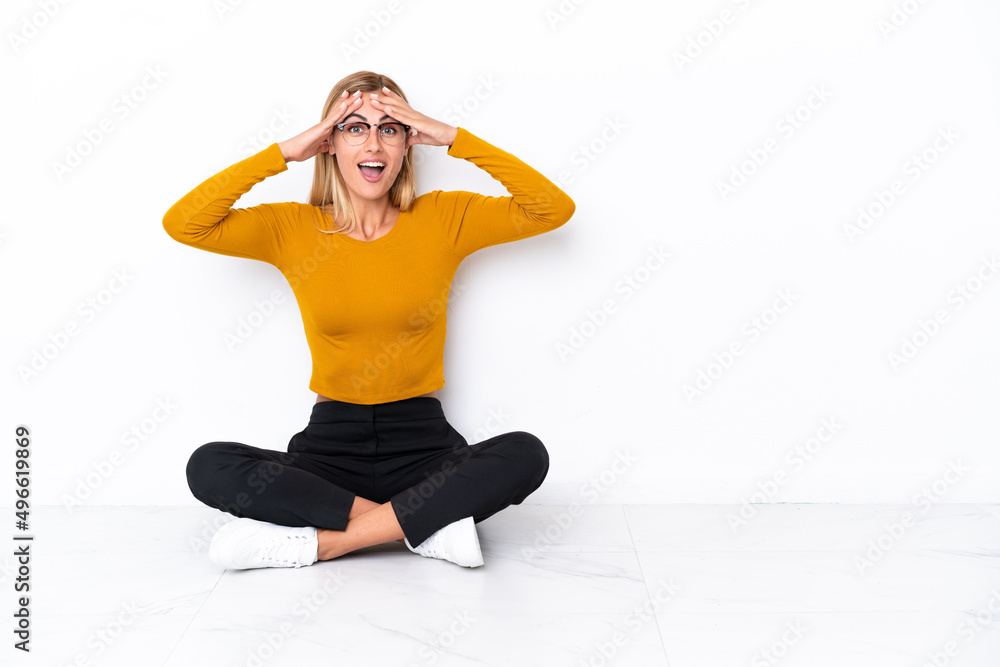 Blonde Uruguayan girl sitting on the floor with surprise expression