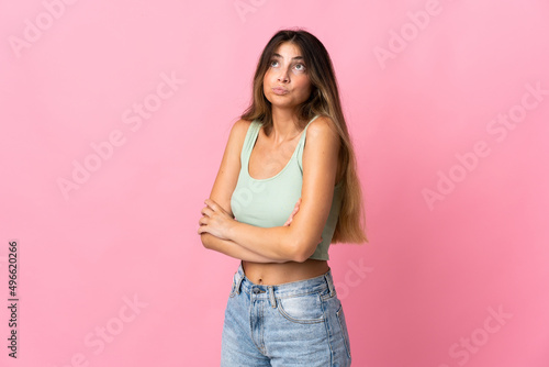 Young caucasian woman isolated on pink background making doubts gesture while lifting the shoulders