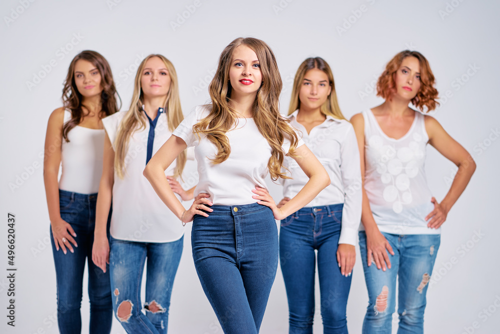 Studio portrait of five young happy attractive smiling caucasian women dressed in jeans grouped together Studio portrait of five young happy attractive smiling caucasian women dressed in jeans grouped together