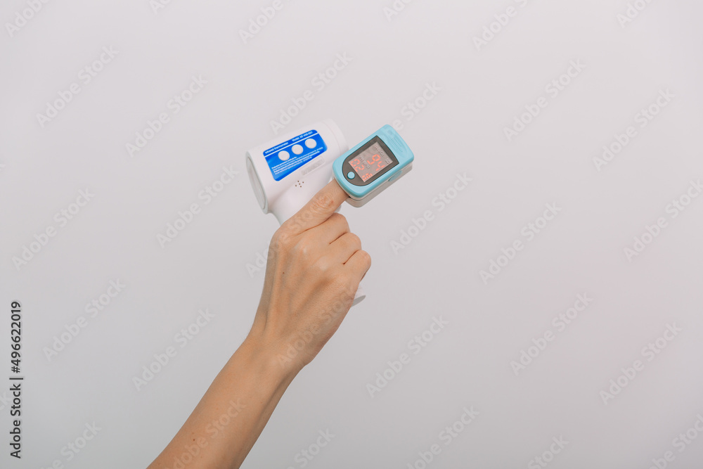Pulse oximeter and thermometer gun on white background. Infrared isometric thermometer gun to check body temperature for virus symptoms. Measuring oxygen saturation, pulse rate and oxygen levels. Pulse oximeter and thermometer gun on white background. Infrared isometric thermometer gun to check body temperature for virus symptoms. Measuring oxygen saturation, pulse rate and oxygen levels.