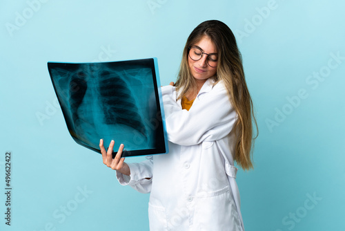 Professional traumatologist isolated on blue background suffering from pain in shoulder for having made an effort