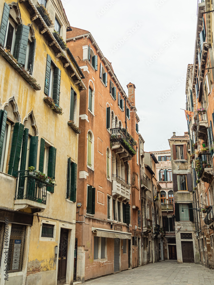 A quiet, empty Venetian street with beautiful pastel colored buildings taken during the winter on an overcast day - Venice, Italy.