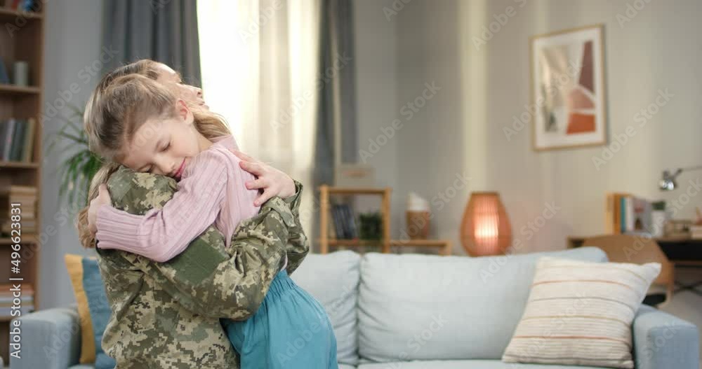 Woman in military uniform embracing with daughter at home Woman in military uniform embracing with daughter at home
