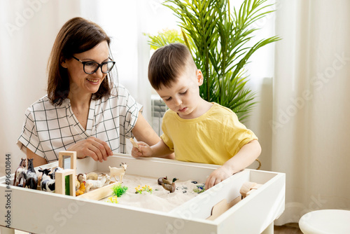 Montessori material. Little boy with his mom explores the farm animals in the game.