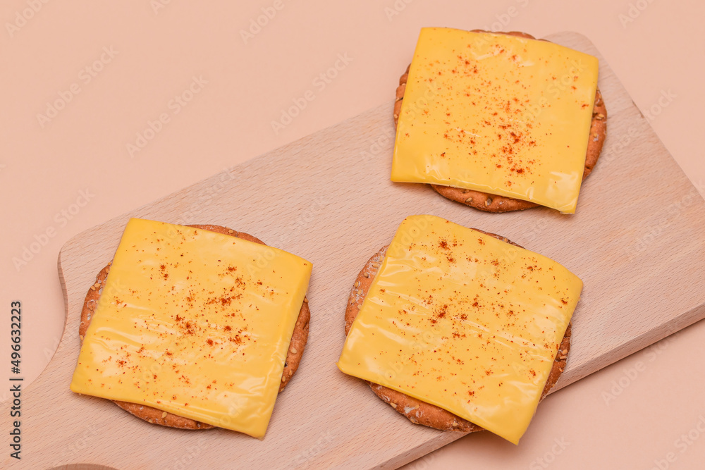 Crispy Cracker Sandwiches with Cheese and Paprika on Wooden Cutting Board and Beige Background Crispy Cracker Sandwiches with Cheese and Paprika on Wooden Cutting Board and Beige Background