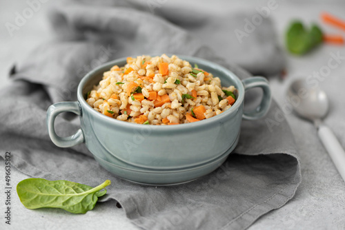 boiled barley porridge with vegetables in a gray plate