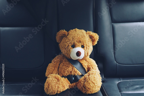Foto Brown teddy bear wearing car seat belt