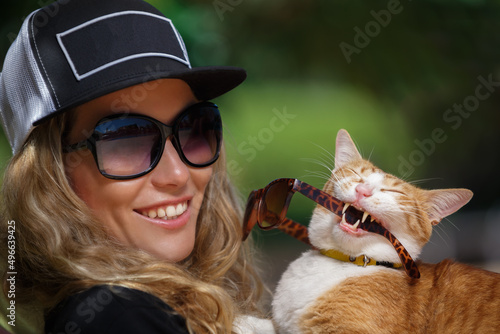 A woman and a cat having fun near the outdoor swimming pool they are sunbathing