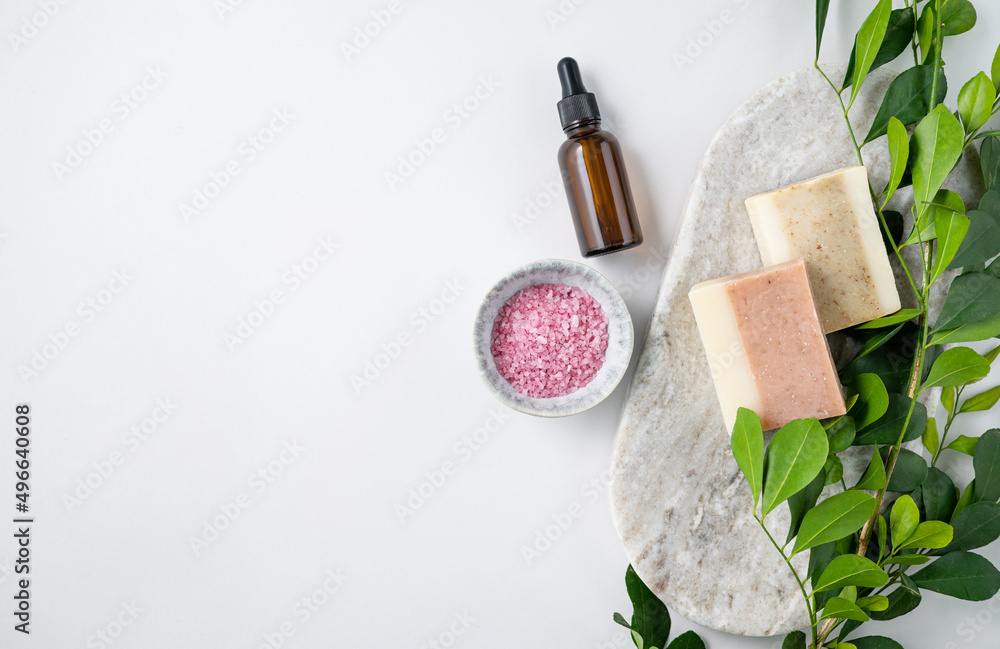 Concept flat lay of facial and body care cosmetics with pink sea salt, soap and cream on white background with brunch. Top view and copy space Concept flat lay of facial and body care cosmetics with pink sea salt, soap and cream on white background with brunch. Top view and copy space