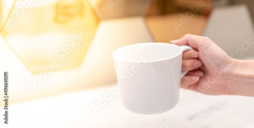 Hand holding a white cup preparing to pour the water with the white background.