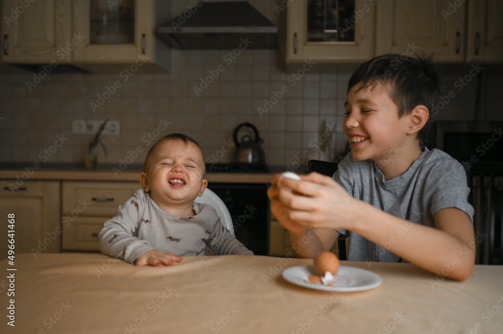 two brothers are sitting in the kitchen and eating an egg two brothers are sitting in the kitchen and eating an egg