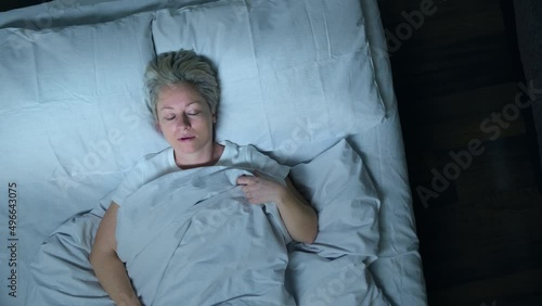 Sleeping man talking in his sleep in bed, top view. Woman suffering from parasomnia sleep disorders. photo