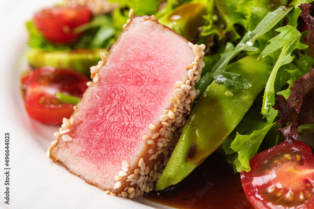 Closeup of tuna steak with sesame seeds and fresh salad