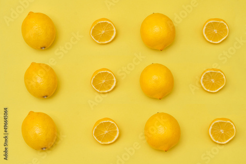 Lemon with halves and whole ripe lemons on yellow background