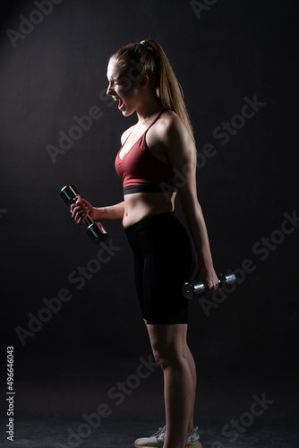 Stands beautiful a A on girl black background with dumbbells Keira Knightley girl dumbbells fitness caucasian, In the afternoon health fit in young and active isolated, beautiful wellness. © Ilya