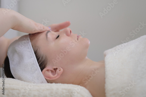 Woman receiving head massage. Calm patient woman undergoing the cosmetic facial massage procedures for rejuvenation skin face