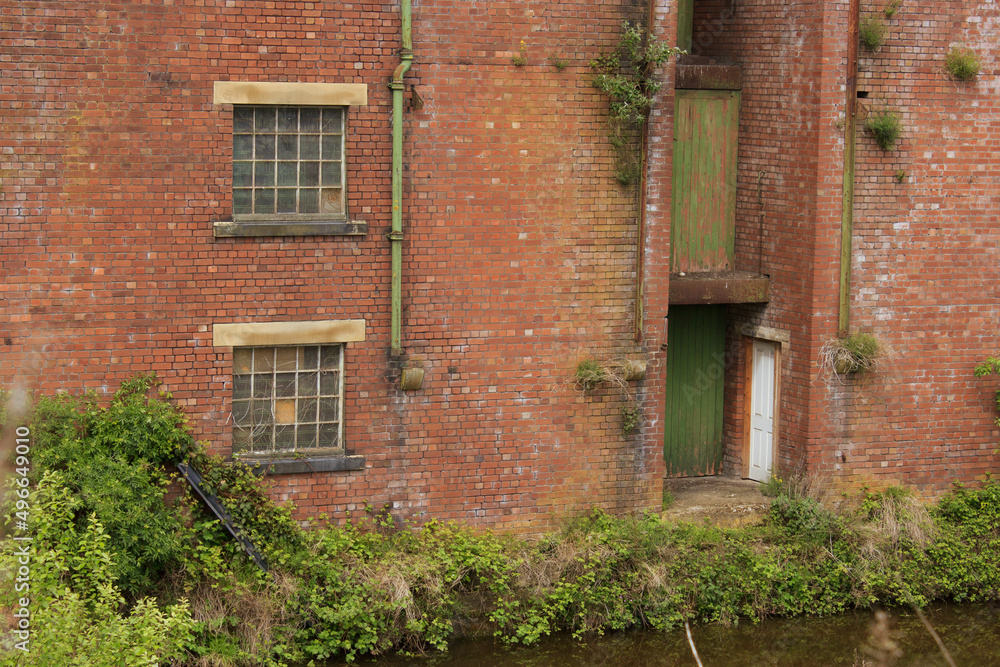 Doors of an old red brick warehouse in Shipley Yorkshire open directly on to the canal where once boats would have moored to load and unload cargo