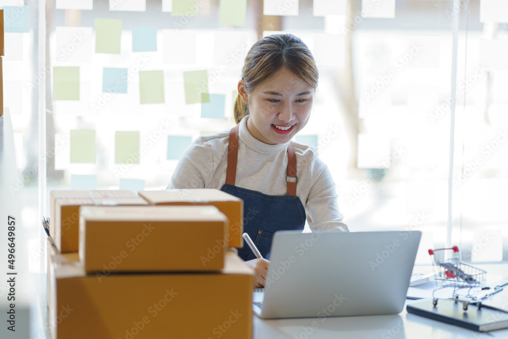 Attractive Asian woman online working in office desk use laptop computer, online marketing packaging box delivery, SME e-commerce concept . Attractive Asian woman online working in office desk use laptop computer, online marketing packaging box delivery, SME e-commerce concept .