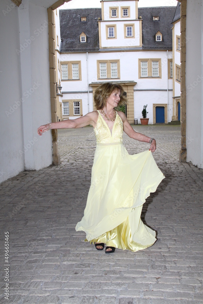 Obraz premium attractive woman in an evening dress walks through a gate in the neuhaus castle near paderborn