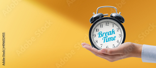 Hand holding a vintage alarm clock with break time message photo