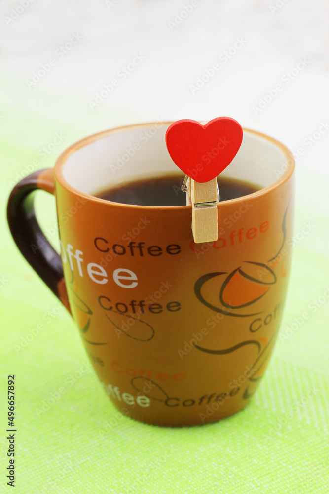 Cup of coffee with wooden clip with red heart