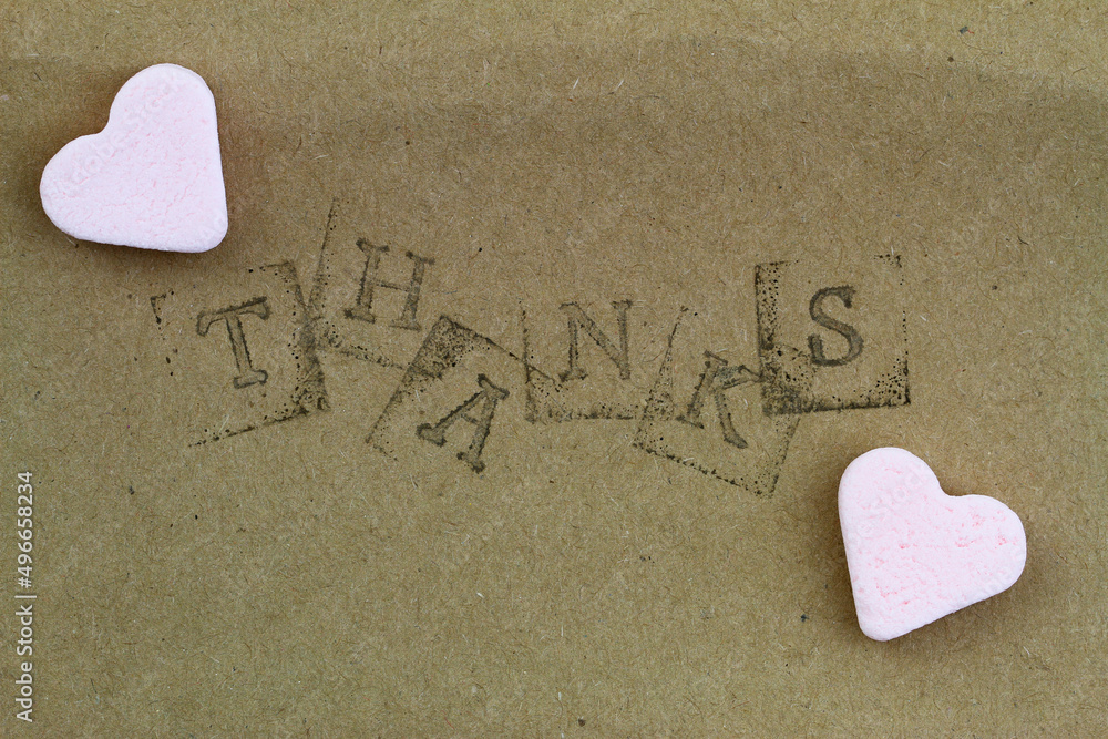 Word thanks made with letter stamps with two pink sugar hearts