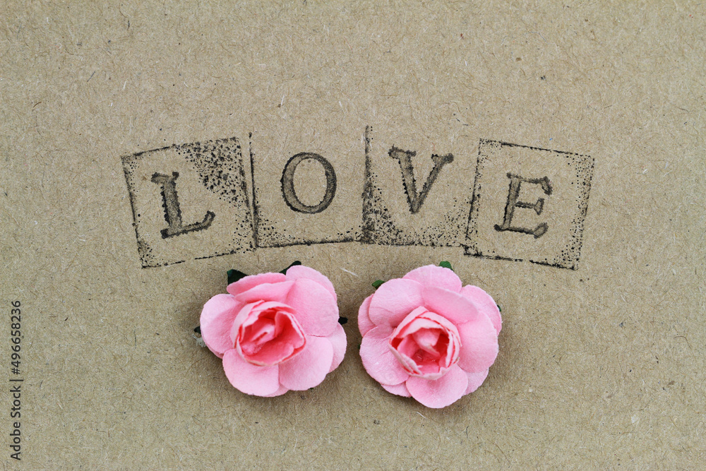 Word love made with letter stamps and two pink paper roses
