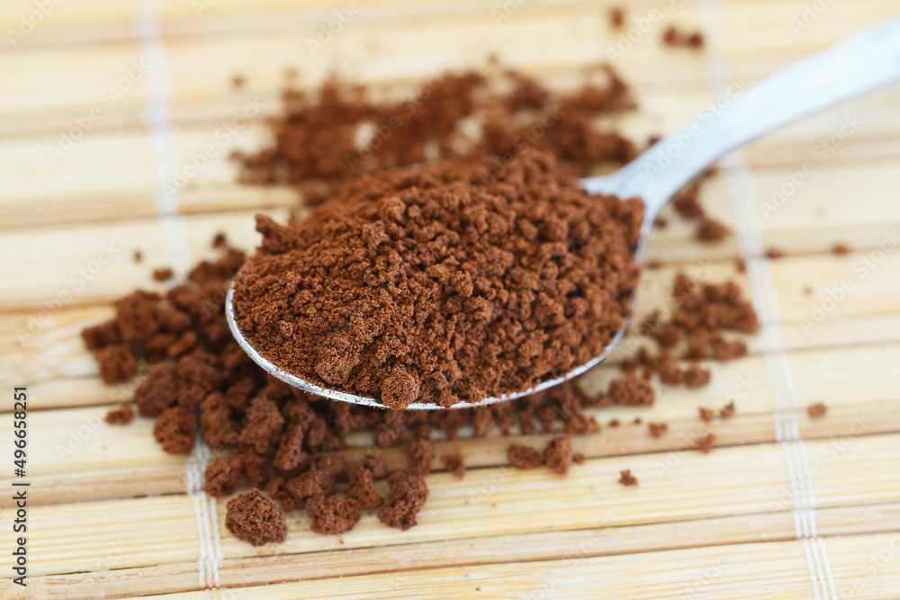 Instant coffee on spoon on bamboo mat, closeup
