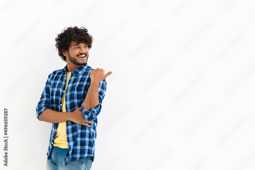 Young Asian man with curly hair and casual stylish clothes smiling with his finger pointing on a white background with copy space, smiles friendly Young Asian man with curly hair and casual stylish clothes smiling with his finger pointing on a white background with copy space, smiles friendly