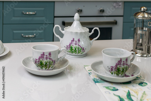 white with lilac flowers tea set on a white table